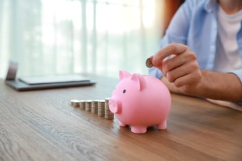 A person putting money into a piggy bank. 